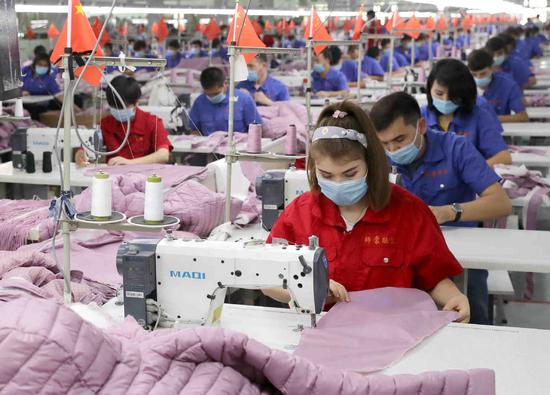 Workers make down-filled coats at a factory in Jiashi county, Xinjiang Uygur autonomous region. （WANG ZHUANGFEI/CHINA DAILY）