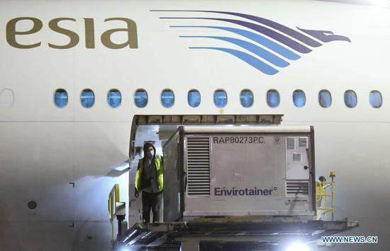 A worker unloads vaccine supplies from China's Sinovac at the Soekarno-Hatta International Airport in Tangerang district of Banten Province in Indonesia, Dec. 6, 2020. COVID-19 vaccines from China were in good condition upon arrival in Indonesia and refrigeration vehicles for delivery have been well prepared to keep the vaccines undamaged and safe, Health Minister Terawan Agus Putranto said on Monday. A vaccine storage warehouse has also been prepared to accommodate 1.2 million doses of the Sinovac vaccine from China with cold chain management following the procedures, he said, adding that the COVID-19 vaccines were expected to be distributed to provincial health offices in several parts of Indonesia before being sent to district or city health offices.(Muchlis Jr/Presidential Palace/Handout via Xinhua)