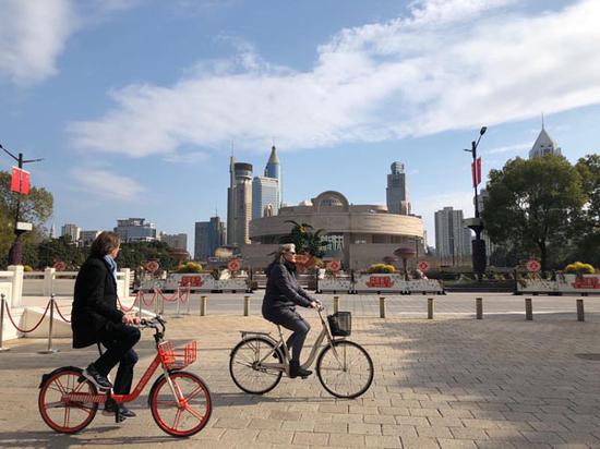 Two foreigners ride bicycles past the Museum of Shanghai in the city center. （PHOTO BY XU XIAOMIN/CHINA DAILY）