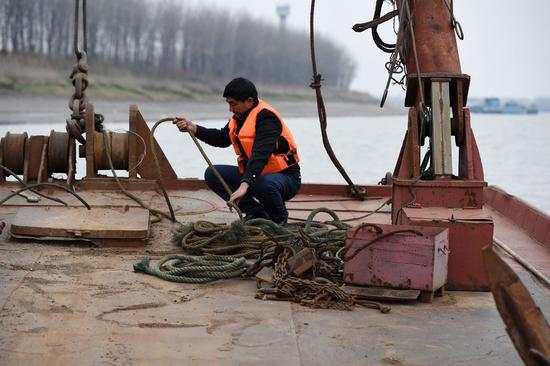 Ex-fisherman Wang Gende arranges ropes on an engineering boat in Anqing, east China's Anhui Province, Dec. 16, 2020. (Xinhua/Zhou Mu)