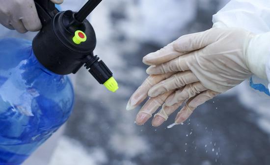 A worker disinfects hands at a community in Dongchang District of Tonghua City, northeast China's Jilin Province, Jan. 17, 2021. (Xinhua/Xu Chang)