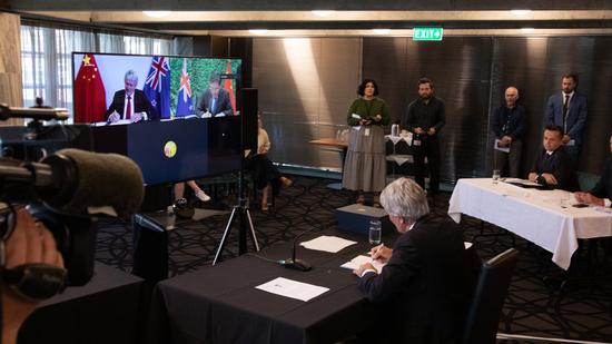 Photo taken in Wellington shows Chinese Minister of Commerce Wang Wentao and his New Zealand counterpart Damien O'Connor signing the FTA protocol via video link on Jan. 26, 2021. (Xinhua)