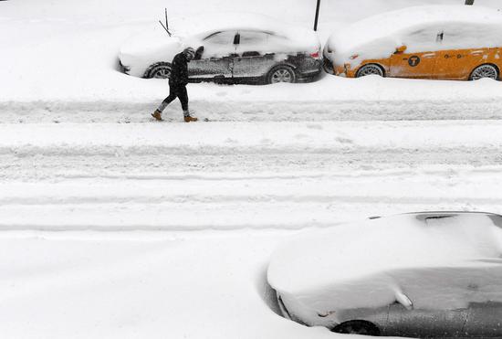 A man walks past snow-covered vehicles in New York, the United States, on Feb. 1, 2021. (Xinhua/Li Rui)