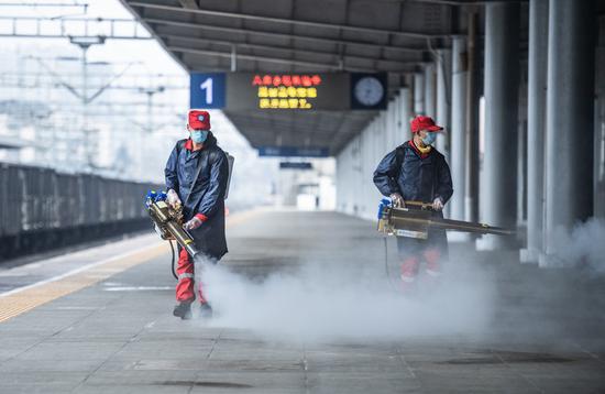 Volunteers disinfect the platform of Liupanshui Railway Station in Liupanshui, southwest China's Guizhou Province, Jan. 28, 2021. (Xinhua/Tao Liang)