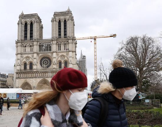 People wearing masks walk past the Notre Dame de Paris cathedral in Paris, France, Feb. 3, 2021. (Xinhua/Gao Jing)