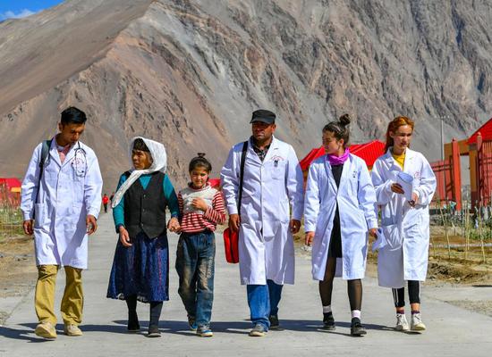 Doctors are seen on their way to provide diagnosis and treatment at the resettlement community for relocated residents of Rasekam Village in Taxkorgan Tajik Autonomous County, northwest China's Xinjiang Uygur Autonomous Region, July 7, 2019. (Xinhua/Wang Fei)