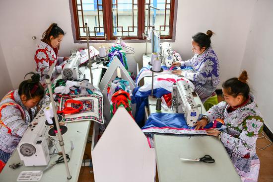 Yang Wenli (L,back) of Miao ethnic group makes Miao costumes with colleagues at a poverty-alleviation workshop in Huawu Village, Qianxi County of Bijie City, southwest China's Guizhou Province, Feb. 20, 2021. (Xinhua/Yang Wenbin)