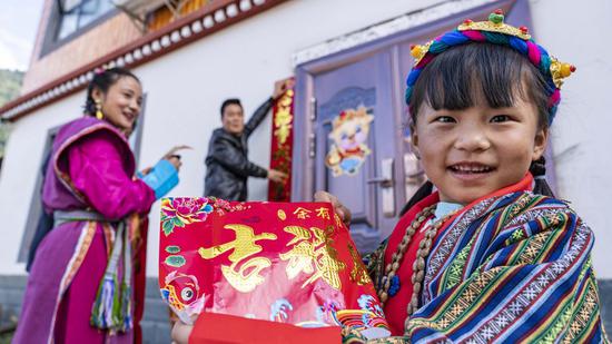 Family members paste couplets to celebrate the Tibetan New Year and Chinese Lunar New Year, which coincided this year, in Medog, southwest China's Tibet Autonomous Region, Feb. 11, 2021. (Xinhua/Sun Fei)