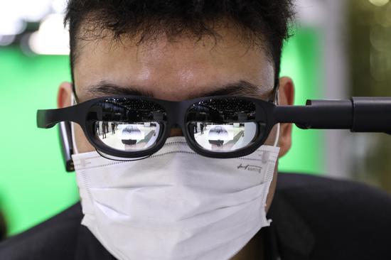 A visitor looks through intelligent virtual-reality glasses, developed by Huawei Technologies Co, at the opening of the Mobile World Congress Shanghai 2021 on Tuesday. The event runs through Thursday. (Photo: China News Service/Zhang Hengwei) 