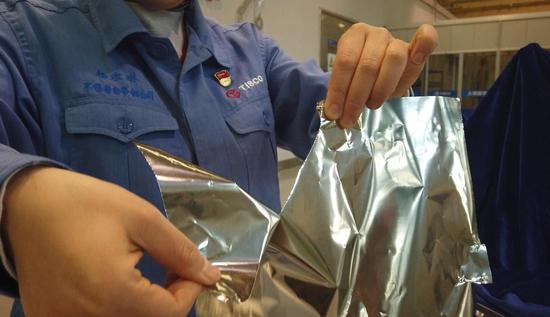 Video screenshot shows an employee showing the wide super-thin precision stainless steel strips, or "hand-tearable steel," at China Baowu Taigang Stainless Steel Precision Strip Co., Ltd. in Taiyuan, north China's Shanxi Province, Feb. 18, 2021. (Xinhua/Wang Hao)