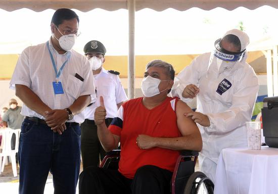 Bolivian President Luis Arce (L) looks on as a medical worker administers a dose of Chinese Sinopharm COVID-19 vaccine to a recipient in Santa Cruz, Bolivia, Feb. 25, 2021. (Photo by Rodrigo Urzagasti/Xinhua)