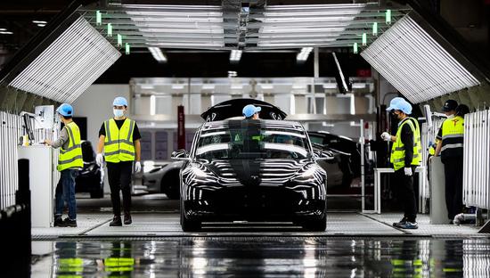 Employees put finishing touches to a vehicle at Tesla's gigafactory in Shanghai on Nov 20. (Photo/Xinhua)