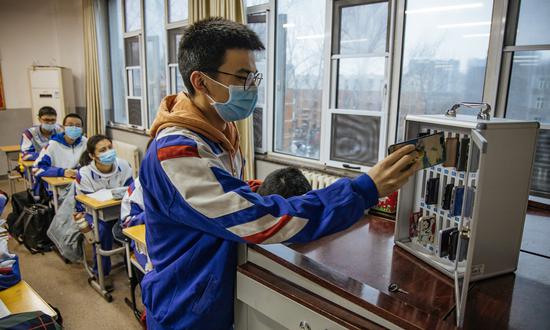 A student in Beijing Jinyuan School puts his mobile phone into the safe deposit box installed in the classroom on March 1, the first day of the new semester. (Photo: Li Hao/GT)