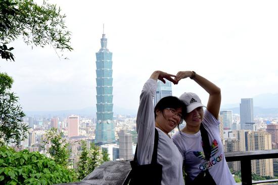 Tourists pose for a photo at Xiangshan Mountain in Taipei, southeast China's Taiwan, July 21, 2019. (Xinhua/Zhu Xiang)