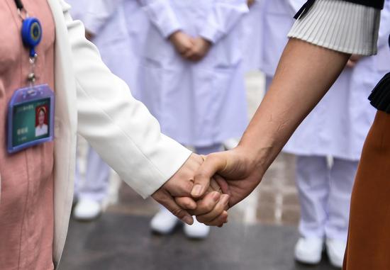 Cai Weimin (R), a former member of the medical team supporting Wuhan from Beijing Hospital of Traditional Chinese Medicine, holds the hand of Hu Juanjuan, head nurse of the west campus of the Union Hospital in Wuhan, central China's Hubei Province, Sept. 23, 2020. A dozen of medical workers from Beijing, who had been in Wuhan to support the fight against the COVID-19 epidemic, revisited Wuhan and reunited with their colleagues there after nearly six months. (Xinhua/Li He)