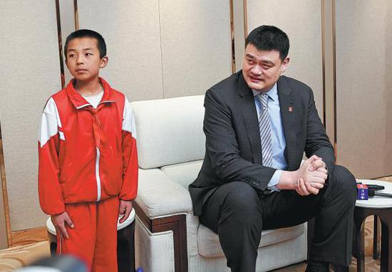 Twelve-year-old Wang Lei, whose hoops skills have propelled him to fame online, stands beside his idol Yao Ming during a basketball forum in Yinchuan, Ningxia Hui autonomous region on Friday. （CHINA DAILY）