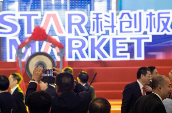 An attendee takes a snapshot at the launch ceremony of the STAR Market in Shanghai. (Photo by Wu Jun/For China Daily)