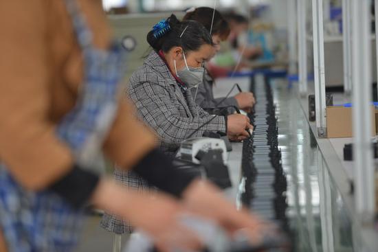 Staff members work on a speaker production line of an electronics company in Linquan County of Fuyang City, east China's Anhui Province, April 16, 2021. (Photo by Lu Qijian/Xinhua)