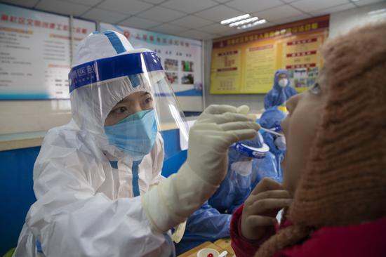 A medical worker collects a swab sample from a child in Harbin, Northeast China's Heilongjiang Province, Jan 14, 2021. (Photo/Xinhua)