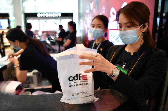 This photo taken on April 19, 2021, shows staff members helping customers at a duty-free store in Boao, Hainan province. (Photo/Xinhua)