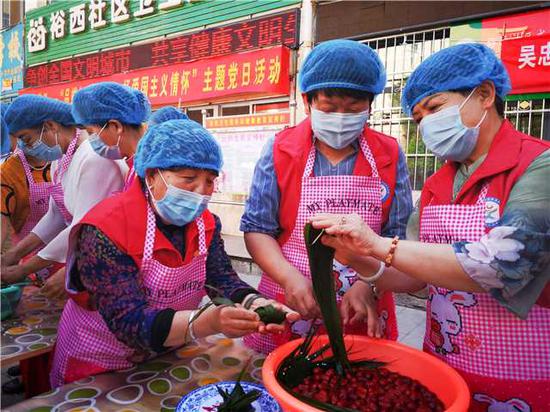 Wang Lanhua (first from left in front) makes zongzi, a festive food for the Dragon Boat Festival, with fellow community residents in Wuzhong, Ningxia Hui autonomous region, in June last year. (Photo/China Daily)