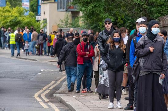 People line up outside Bridge Park Community Leisure Center to receive COVID-19 vaccines in Brent, northwest London, Britain, June 19, 2021. (Photo by Ray Tang/Xinhua)