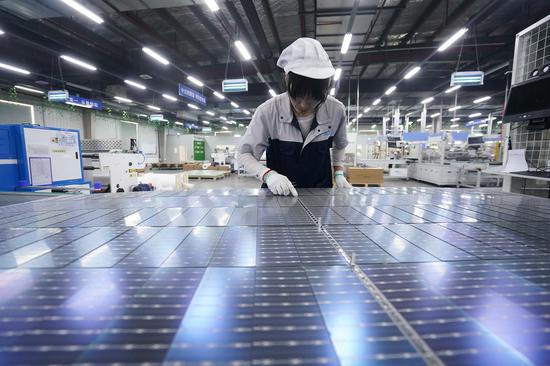 An employee checks photovoltaic panels at a production facility in Suqian, Jiangsu province, in May. (Photo/Xinhua)
