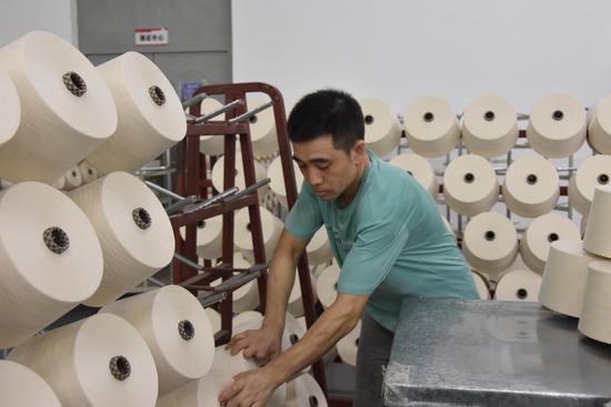 A worker packs spindles at a textile plant in Shihezi City, northwest China's Xinjiang Uygur Autonomous Region, July 7, 2021. (Xinhua/Gu Yu)