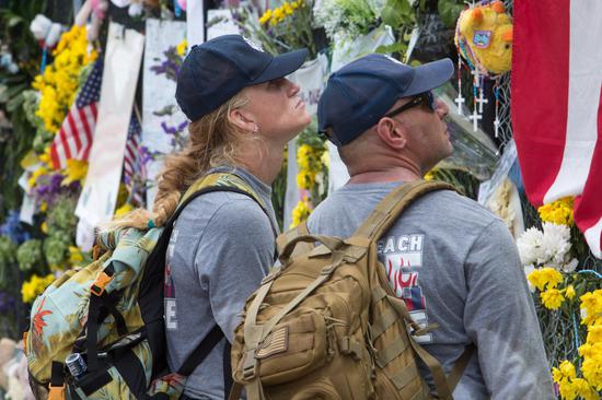 Rescuers pause at a memorial wall around the site of the collapsed building after their shift in Miami-Dade County, Florida, the United States, July 7, 2021. (Photo by Monica McGivern/Xinhua)