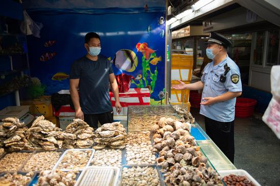 A market supervision official inspects a seafood market in Beijing on June 16, 2020. [Photo/Xinhua] 