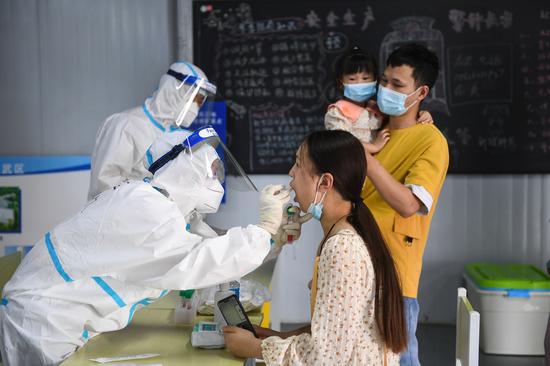 A medical worker takes a swab sample from a woman for COVID-19 test at a testing site in Nanjing, East China's Jiangsu province, July 29, 2021.(Photo/Xinhua)