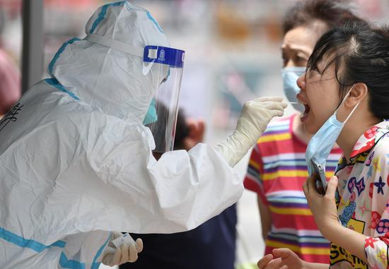 A medical worker in protective suit collects a swab sample from a woman for COVID-19 nucleic acid testing in the subdistrict of Baihedong in Liwan district of Guangzhou, South China's Guangdong province, June 12, 2021. [Photo/Xinhua]