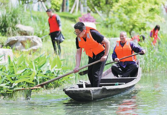 Volunteers clean a lake at the Luoshui wetland in Deqing, Huzhou city, Zhejiang province, on April 21. (WANG ZHENG/FOR CHINA DAILY)