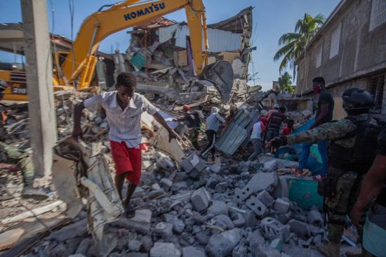 People remove debris after an earthquake, in Les Cayes, Haiti, on Aug. 15, 2021. (Photo by Richard Pierrin/Xinhua)