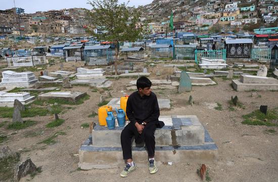 An Afghan boy sells water at a graveyard where a number of war victims have been buried in Kabul, Afghanistan, on April 16, 2021. Since entering Afghanistan in October 2001, the U.S. troops have caused more than 30,000 civilian deaths, injured more than 60,000 and made about 11 million people become refugees. (Photo by Rahmatullah Alizadah/Xinhua)