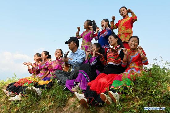 Girls and their teacher sing outdoors at Dacao town of Puge county, Liangshan Yi autonomous prefecture, Southwest China's Sichuan province, Aug 6, 2021. The all-girls choir at Dacao central primary school in Puge county gained wide attention after the videos of their performances are shared on short video platforms. The choir was invited to attend a music festival in Beijing this summer. (Photo/Xinhua)