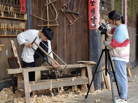 An Xu and his wife Wang Shuangyu make a video of An's carpentry work in Fenggang, Guizhou province, in May. (Photo/Xinhua)
