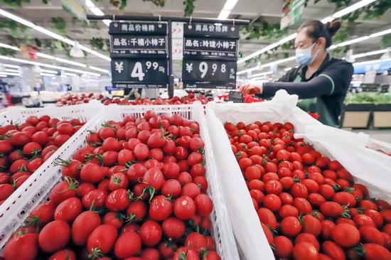 A worker arranges fruits in a supermarket in Zunhua, Hebei province on Aug 17, 2021. (Photo/Xinhua)