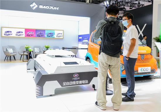 An exhibitor, right, introduces a fully automatic mini power changing station at the World New Energy Vehicle Congress in Haikou, capital of South China's Hainan province, on Sept 15, 2021. (Photo/Xinhua)