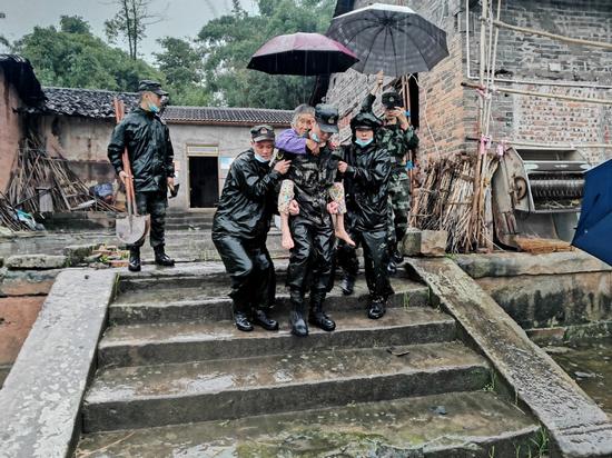 Rescuers transfer a senior woman to a safe location in Fuji town of Luxian county, Southwest China's Sichuan province, on Sept 16, 2021. (Photo: chinadaily.com.cn/Xiang Qian)