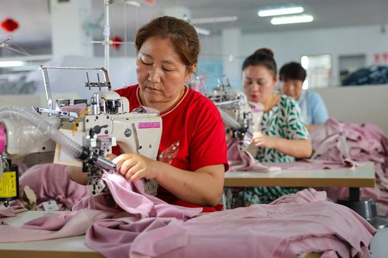 Workers are busy working in a workshop of a garment company in Urumqi, northwest China's Xinjiang Uygur Autonomous Region, Aug. 26, 2021. (Xinhua/Ding Lei)