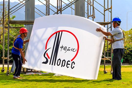 Workers change the billboard at a Sinopec gas station in Fuzhou, Fujian province. (Photo/China Daily)