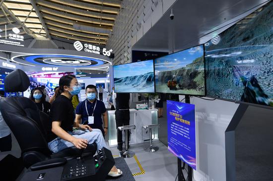 A visitor tries a 5G smart mine shovel cockpit at the Light of Internet Expo in Wuzhen, Zhejiang province, on Sept 25, 2021. (Photo/Xinhua)