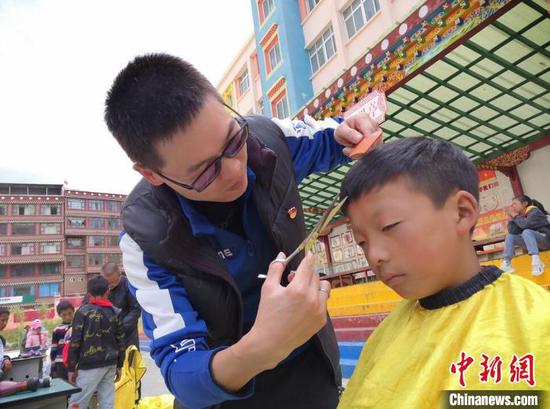 Volunteer teachers is cutting a student's hair. (Photo: China News Service/Liu Xiaoyi)