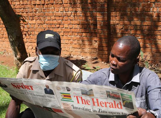 Local residents read The Herald in Harare, Zimbabwe, Oct. 14, 2021. (Photo: Xinhua/Zhang Yuliang)