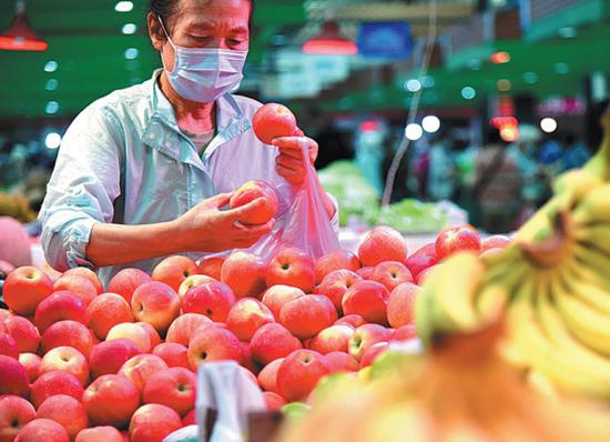 A resident buys apples at a market in Lianyungang, Jiangsu province. (Photo: China Daily/Geng Yuhe)