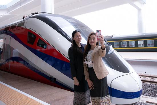Two women pose for photos with the bullet train at the China-Laos railway Vientiane station in the Lao capital Vientiane, Oct 16, 2021. (Photo/Xinhua)