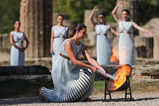 Greek actress Xanthi Georgiou, playing the role of an ancient Greek High Priestess, lights the torch during the Olympic flame lighting ceremony for the Beijing 2022 Winter Olympic Games, in ancient Olympia, Greece, Oct. 18, 2021. (Xinhua/Zheng Huansong)