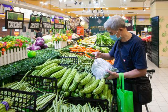A shopper buys vegetables at a supermarket in Nanjing, Jiangsu province. (Photo: China Daily/Su Fang)