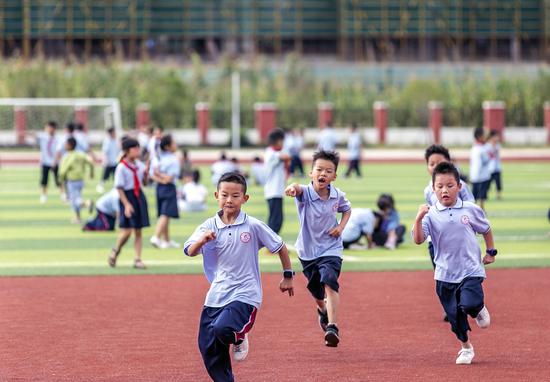 Pupils run on the playground at a primary school in Qianxi city, Southwest China's Guizhou province, on Aug 31, 2021. (Photo/Xinhua)